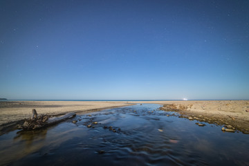 Small stream flows into the sea through the beach.