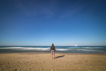 Fototapeta na wymiar Young man on the Baltic seashore looking at the sea late at night