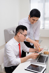 Image of two young businessmen interacting at meeting in office