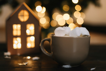Christmas coffee cup with marshmallows. Still life on dark background. New Year's lights and decorations