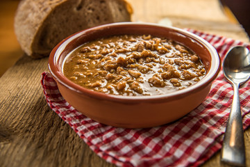 tripe stew sauce in brown ceramic pot on a wood table 