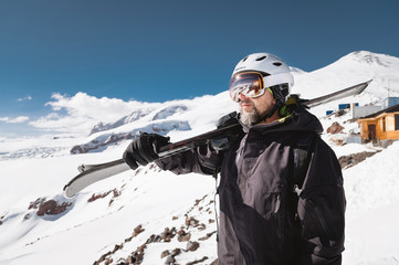 Portrait bearded male skier aged against background of snow-capped Caucasus mountains. An adult man...
