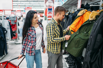 Young couple choosing warm clothes in supermarket