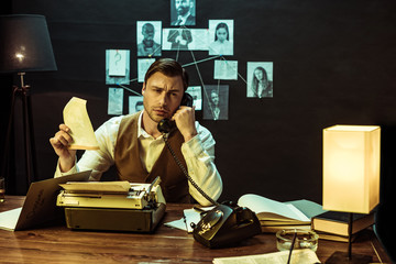 Detective holding document while talking on telephone in office