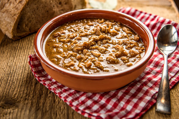 tripe stew sauce in brown ceramic pot on a wood table 