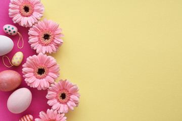 Easter flat lay in yellow and coral colors with painted eggs and gerbera daisy flowers, copy-space