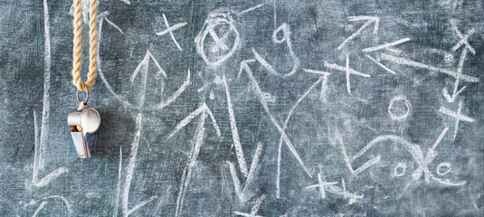 whistle of a soccer or football referee on black board with tactical diagram, free copy space