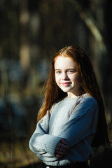 Portrait of cute young girl with long-bright-red hair, outdoors.