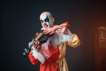 Bloody clown plays the violin with a human hand