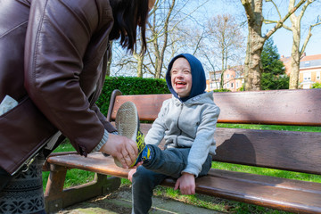  Defect,childcare,medicine and people concept: Happy mother and son with down syndrome playing together in a park.