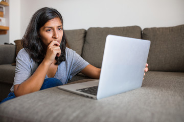 Young indian woman using computer mobile phone at home