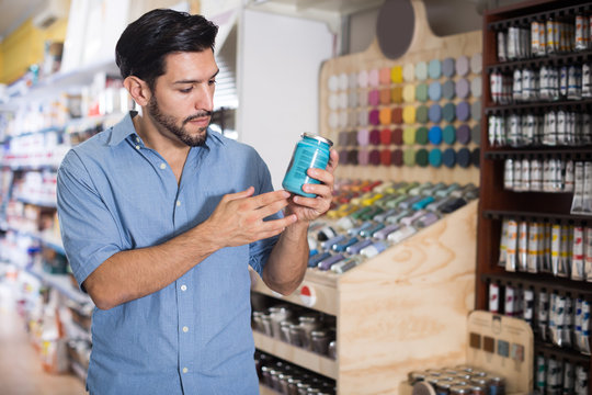 Focused man choosing materials in paint store