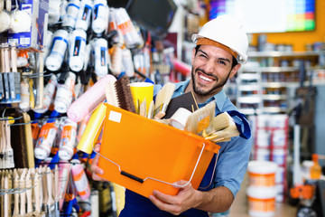 Workman holding basket with picked tools in paint store