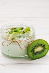 Fototapeta na wymiar Yogurt with kiwi slices on a wooden white background.