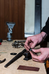 Man hands holding raw silver ring before polishing with jewelry making tools on a background.