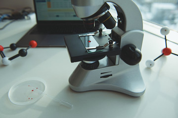 Modern microscope with medical instruments in laboratory