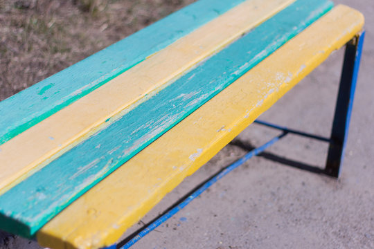 old wooden bench at the entrance of the house, painted in blue and yellow