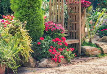 Wood bench in beautiful flower garden setting on side of pathway
