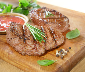 grilled beef steak on a cutting board with spices .