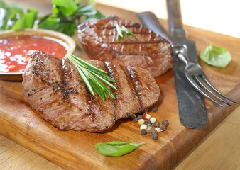grilled beef steak on a cutting board with spices .