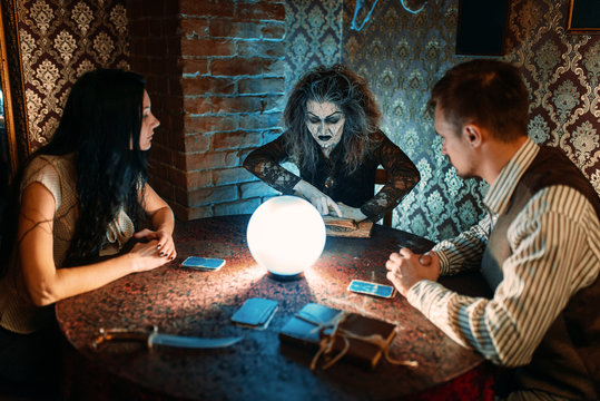 Family and witch at the table with crystal ball