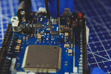 Microcircuit with tweezers on the background of electronic components