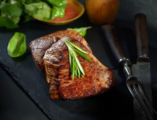 grilled  beef steak on black slate with spices.