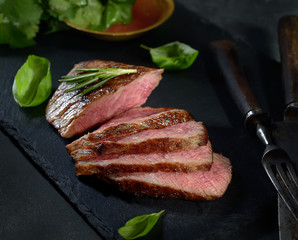 grilled  beef steak on black slate with spices.