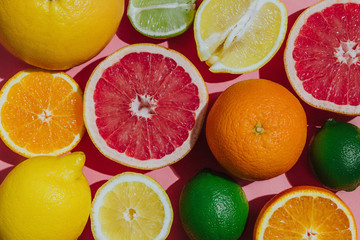 Citrus fruits fresh cutted on a pastel pink background closeup grouped top view