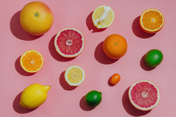 Citrus fruits fresh cutted on a pastel pink background closeup separately top view