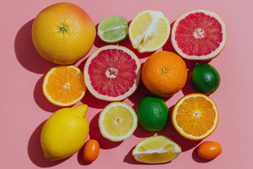 Naklejka na ściany i meble Citrus fruits fresh cutted on a pastel pink background grouped top view