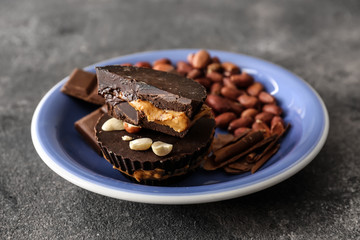 Plate with tasty chocolate peanut butter cups on grey background