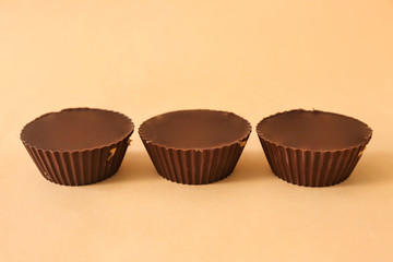 Tasty chocolate peanut butter cups on color background