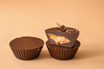 Tasty chocolate peanut butter cups on color background