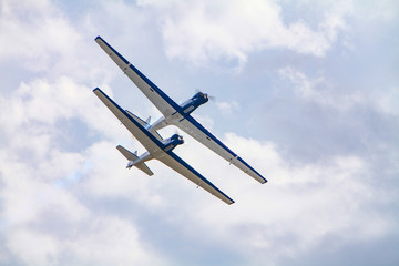 A view of two stunt planes flying overhead in close formation with one aircraft flying directly...