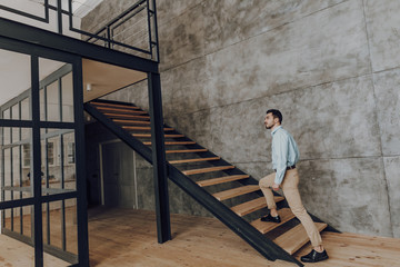 Young trendy man is walking up steps indoors