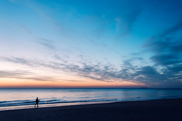 man walking along the seashore at sunset