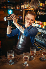 Bartender works with shaker at the bar counter