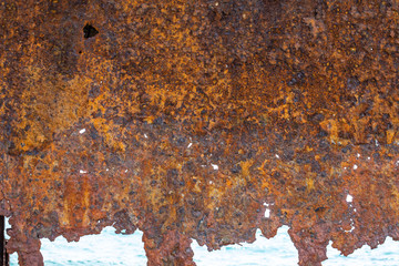 A close up and detailed view of an old rusty metal hull of an abandoned shipwreck.