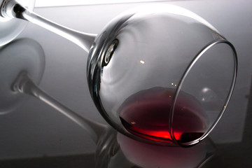 A glass of wine lies on a gray glossy blurred background.