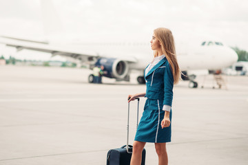Sexy stewardess with suitcase on aircraft parking