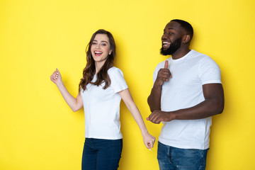 Happy interracial couple in white T-shirts posing for camera in studio