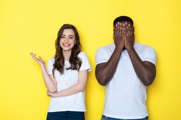 Young interracial couple in white T-shirts posing for camera in studio