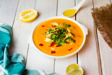 Spicy pumpkin cream soup with seafoods. Oil. Lemon. Homemade. Lunch. Ingridients. Top view. Wooden white table.