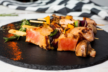 kebab with tuna, mushrooms and vegetables. Rosemary. Black plate. Wooden white table. Homemade. Diet. 