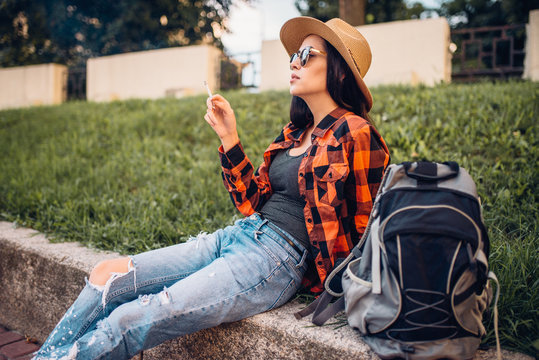 Female tourist in sunglasses smoke cigarettes