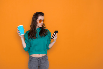 Half length of attractive fashionable Caucasian girl drinking coffee in studio