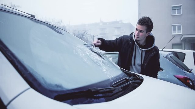 Man Scraping Ice From Car Windshield