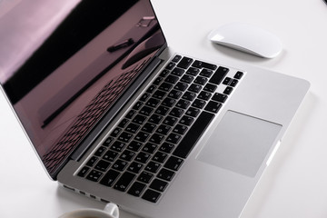 Laptop on a light table with a mouse and a telephone