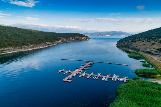 Aerial picture of floating dock with boats, motorboats and vessels floating on water in lake Small Prespes, Northern Greece
